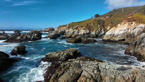 vista panorámica sobre olas borrosas con gorras blancas que se estrellan contra rocas marrones a lo largo de la costa pacífica, autopista 1 california