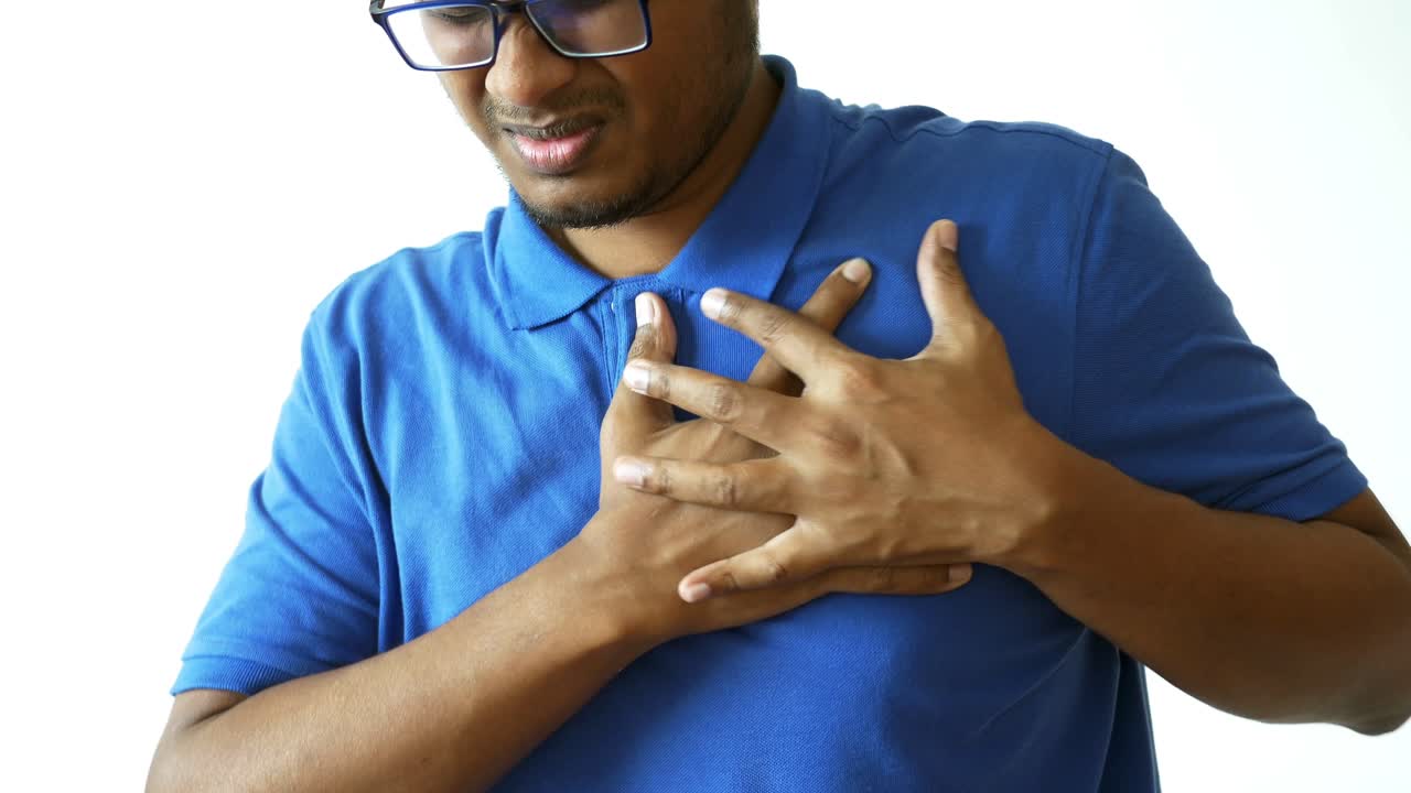 Young man suffering pain in heart and holding chest with hand
