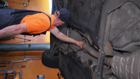 mechanic working on car's undercarriage in a garage