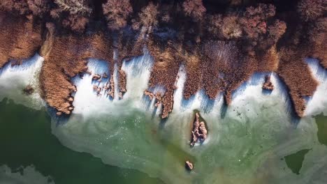 aerial landscape forward shot of barely frozen lake with reeds, szűcsi, hungary, europe