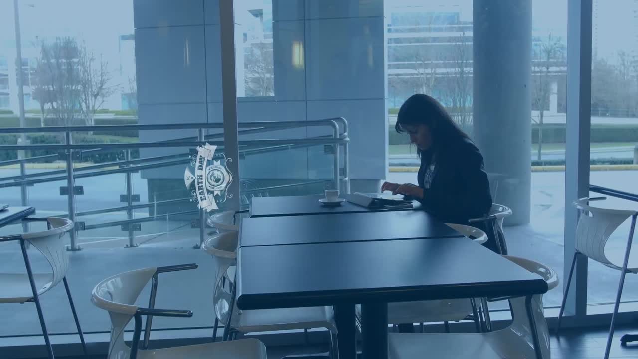 Animação de texto do dia da terra sobre mulher de negócios birracial trabalhando no escritório