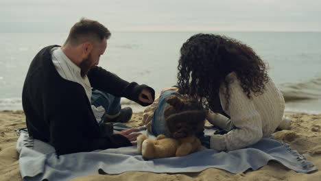 Padres-Niño-Tendido-Playa-Por-La-Naturaleza-De-La-Orilla-Del-Mar.-Familia-Feliz-Jugando-En-Un-Picnic.