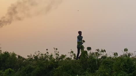 Tracking-shot-man-jogging-outside-with-polluting-burning-gas-plant-behind-at-morning,-day