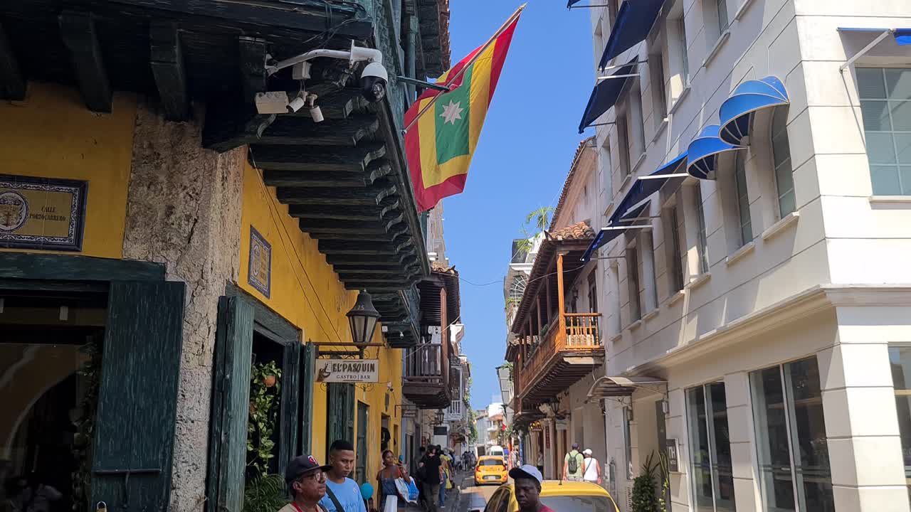 Cartagena Colombia Old Town Street Life on Sunny Day, People and Taxi Cars on Narrow Street Under Colonial Buildings