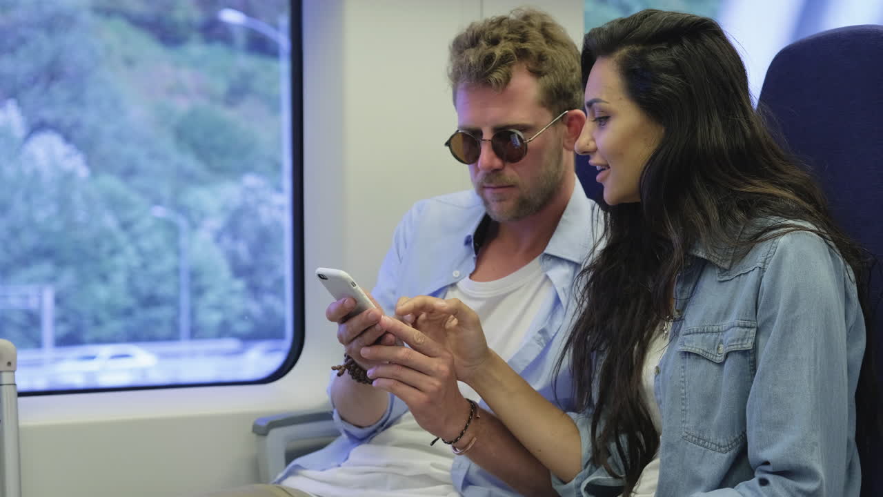 pareja usando un teléfono inteligente en un tren