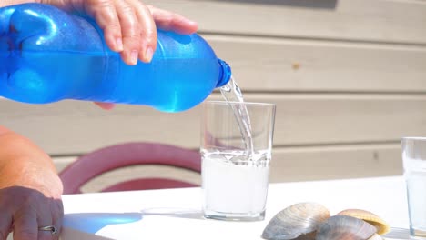 Slow-motion-shot-of-a-drink-being-poured-from-a-blue-bottle-into-an-empty-glass