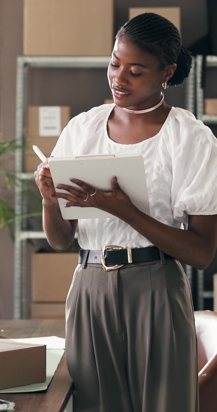 Young Businesswoman Writing on Clipboard in Warehouse Office