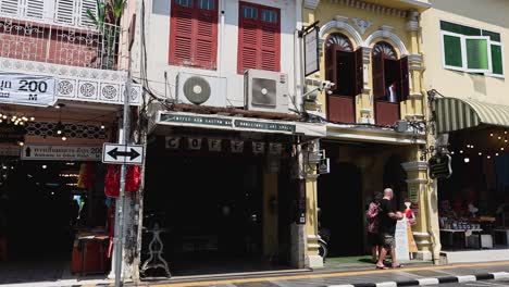 people walking past colorful buildings in phuket