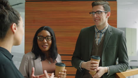 multiethnic coworkers talking over coffee in office