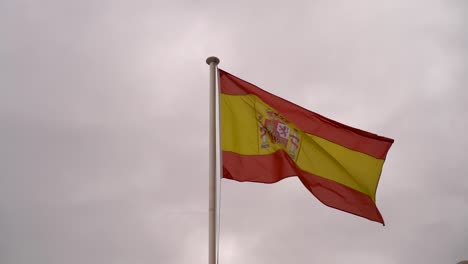 close up of spanish flag waving in slow motion against gray sky