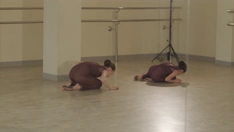 un grupo de jóvenes estudiantes de ballet con ropa de baile negra practicando posiciones en un amplio estudio de ballet con pisos de madera y barras montadas en la pared. expresiones enfocadas y movimientos sincronizados.