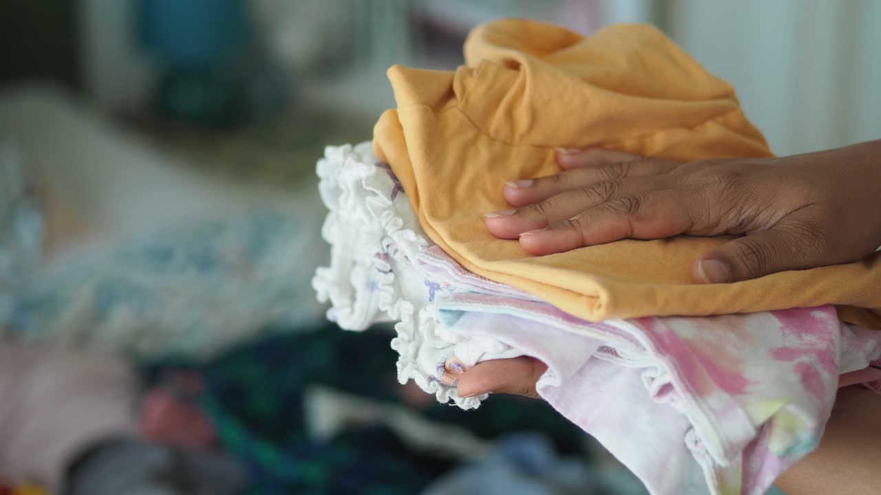Close-up of a hand holding a stack of folded clothes