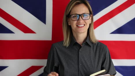 smiling woman with peace sign and notebook in front of uk flag