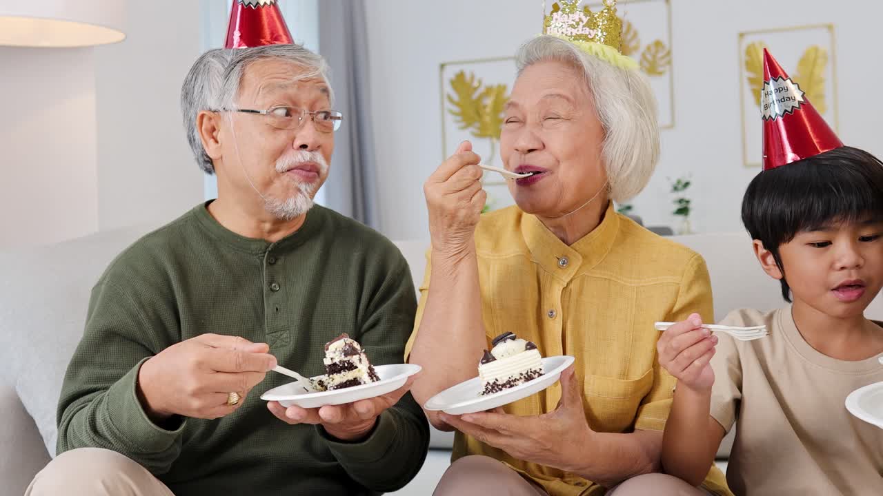 Elderly couple enjoys cake with family in a warm, festive setting. Bright lighting enhances the joyful, intimate atmosphere