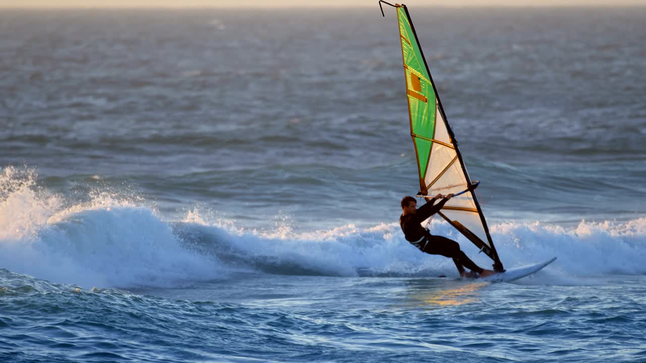 surfista masculino haciendo windsurf en la playa 4k