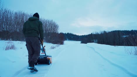 hombre empujando un soplador de nieve, limpiando la nieve en la carretera en indre fosen, noruega