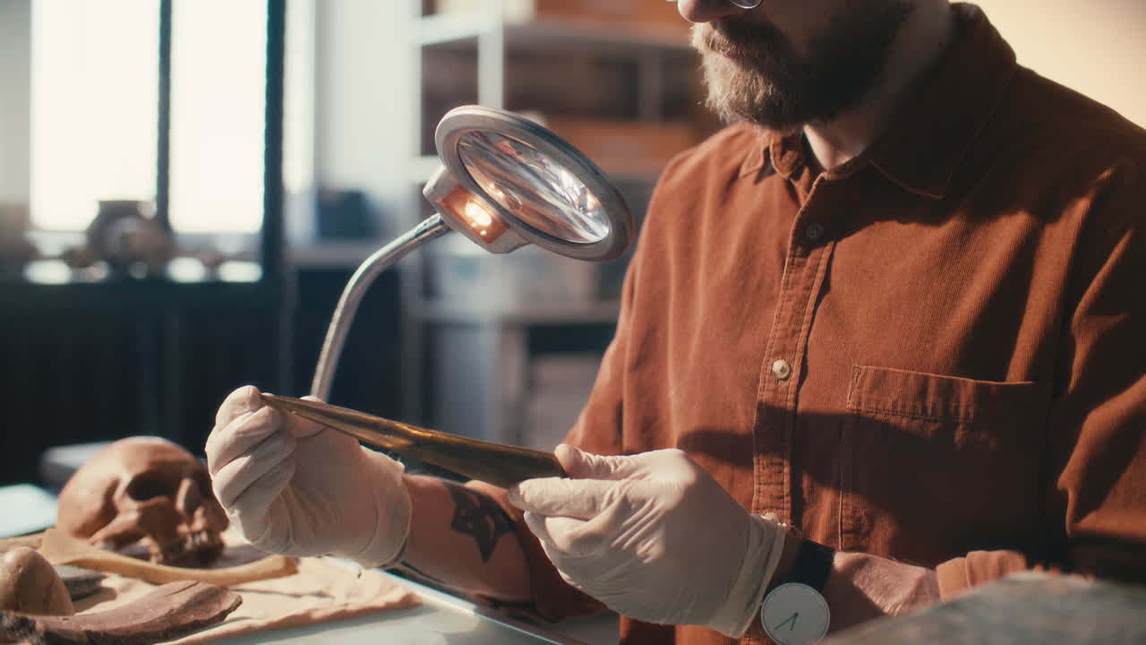arqueólogo profesional observando la punta de la lanza bajo una lámpara de ampliación