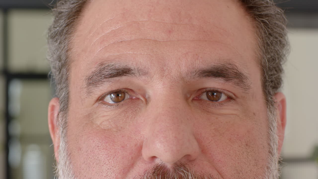 Mature man with thoughtful expression looking directly at camera indoors