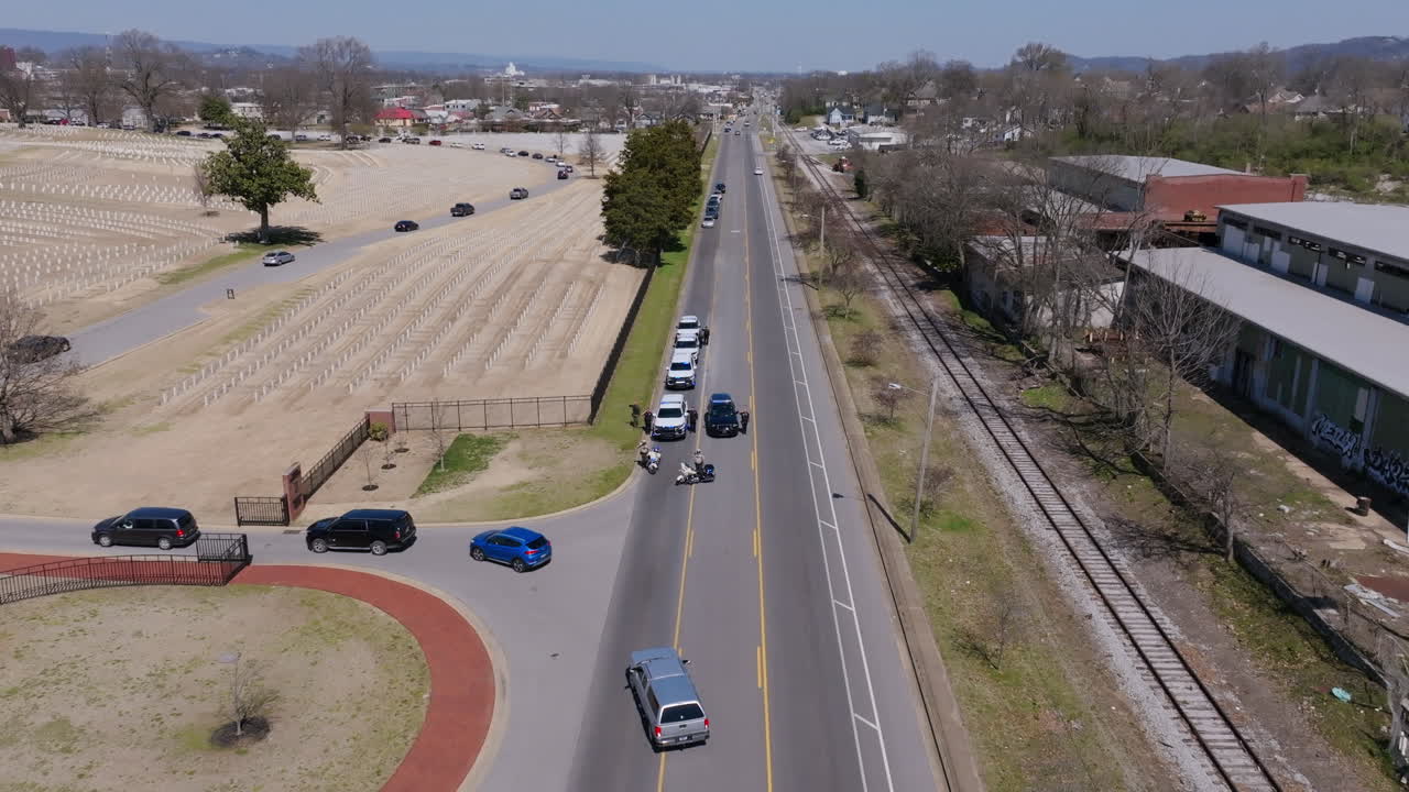 Aerial footage following a funeral procession as it moves through Chattanooga National Cemetery with a police escort blocking the road.