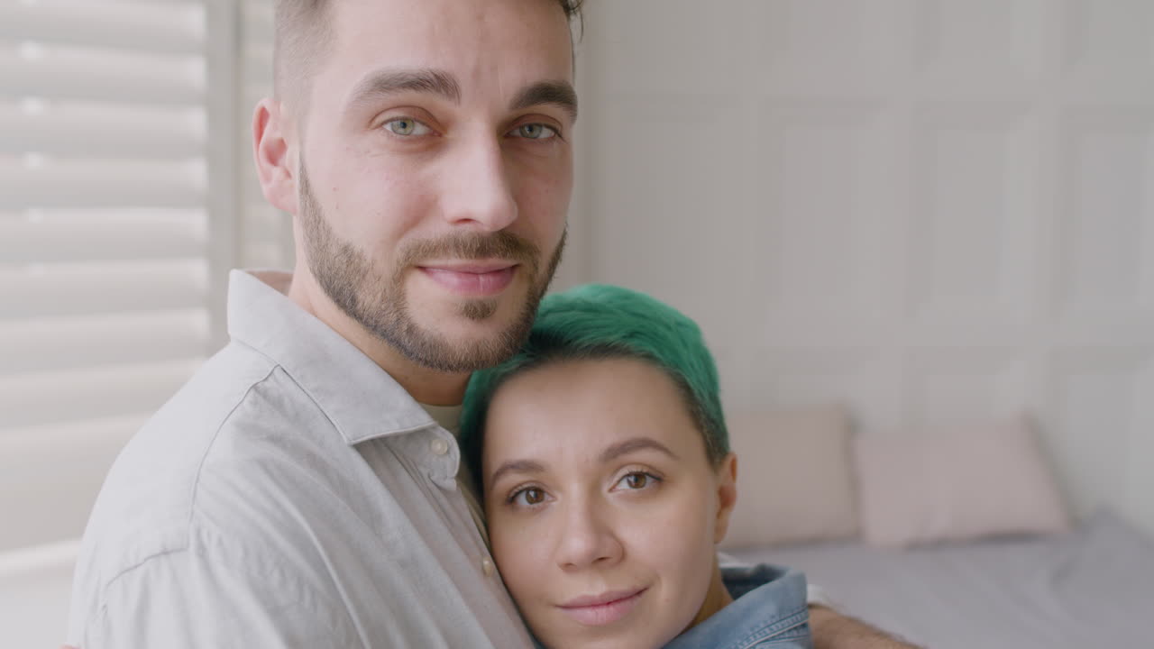 cerca de una pareja amorosa abrazando tiernamente y mirando a la cámara en el dormitorio