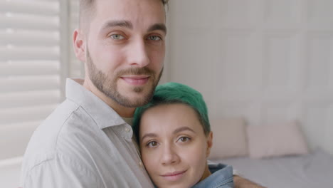 cerca de una pareja amorosa abrazando tiernamente y mirando a la cámara en el dormitorio