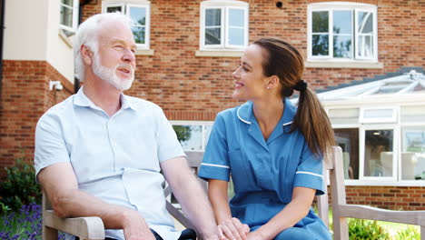 senior man sitting on bench and talking with nurse in retirement home