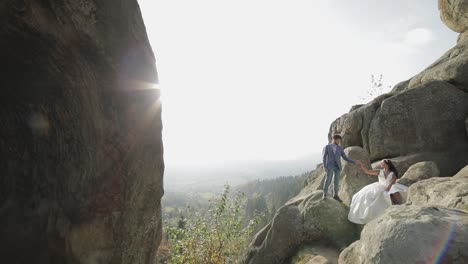 Groom-with-bride-on-a-high-slope-of-the-mountain.-Wedding-couple.-Sunbeams