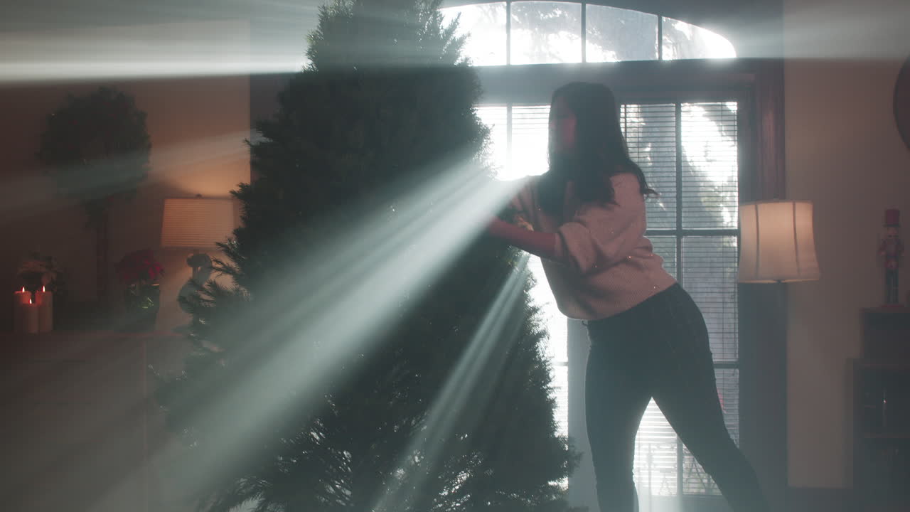 Woman Decorating a Christmas Tree in a Hazy, Light-Filled Room