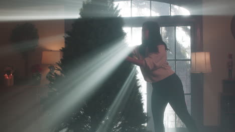 woman decorating a christmas tree in a hazy, light-filled room