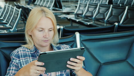 a woman uses a tablet in an airport lounge leisure pending flight