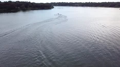 a slo motion aerial shot of some people having fun being pulled behind a jet ski on a tube in a lake in florida