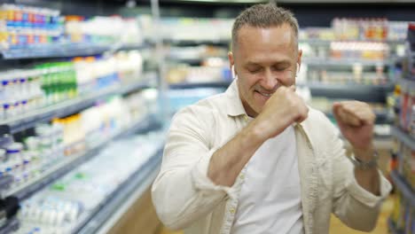 A-middle-aged-shop-shopper-dances-with-earphones-in-the-department.-Happiness