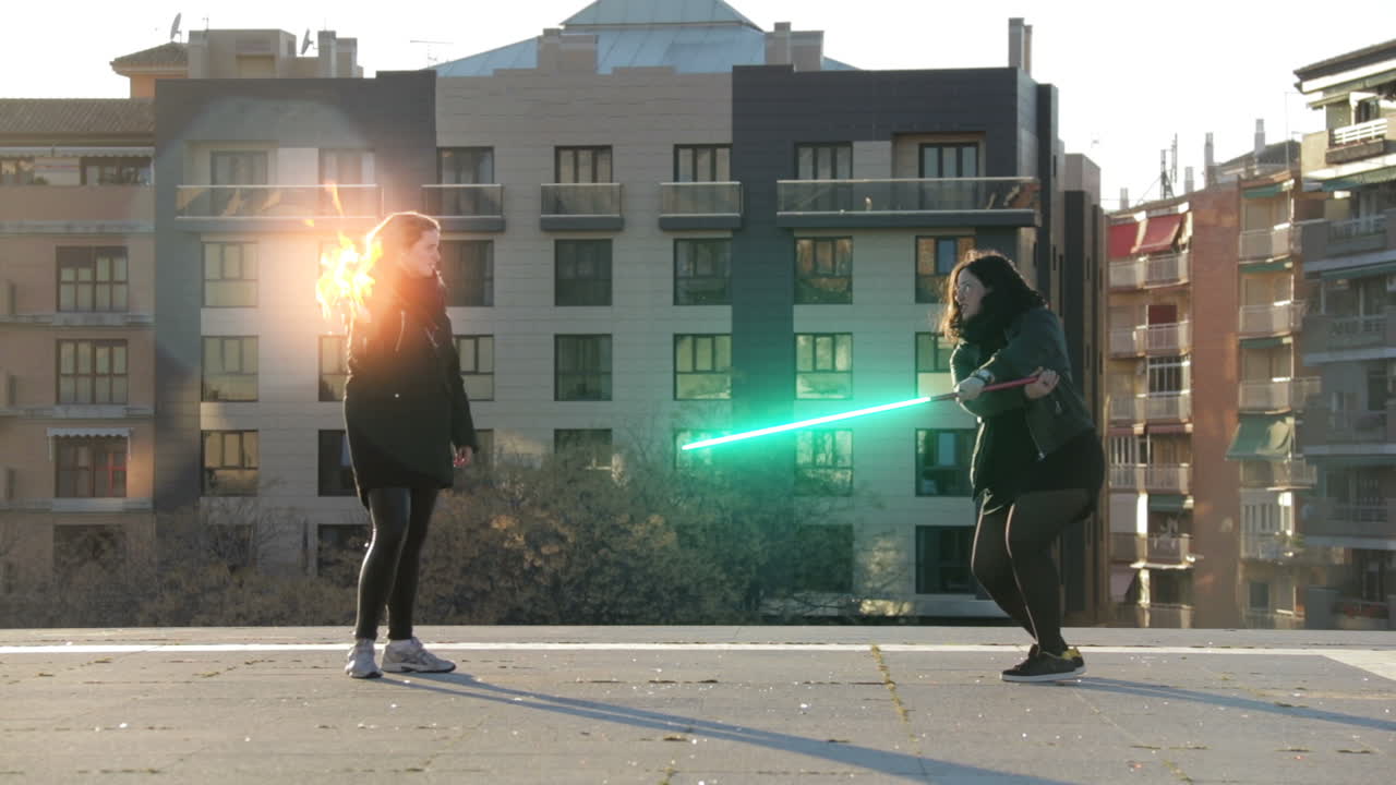 Two women having a lightsaber duel on a rooftop