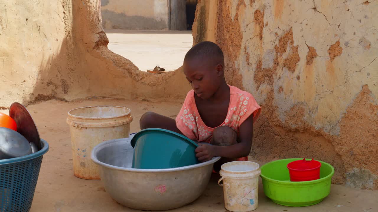 Little cute black african child children washing dish in remote rural village of Africa