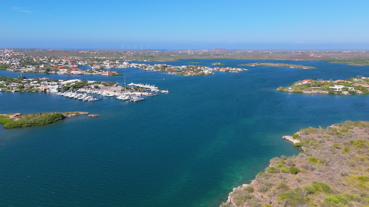 Aerial dolly of yachts anchored by a rugged coastline, clear waters and rocky cliffs below the horizon, views of Seru Kabritu