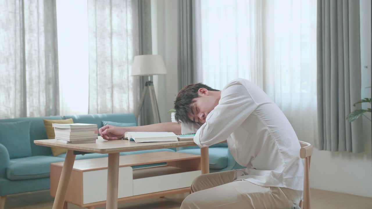 Side View Of Asian Man Student Sleeping While Studying At Home