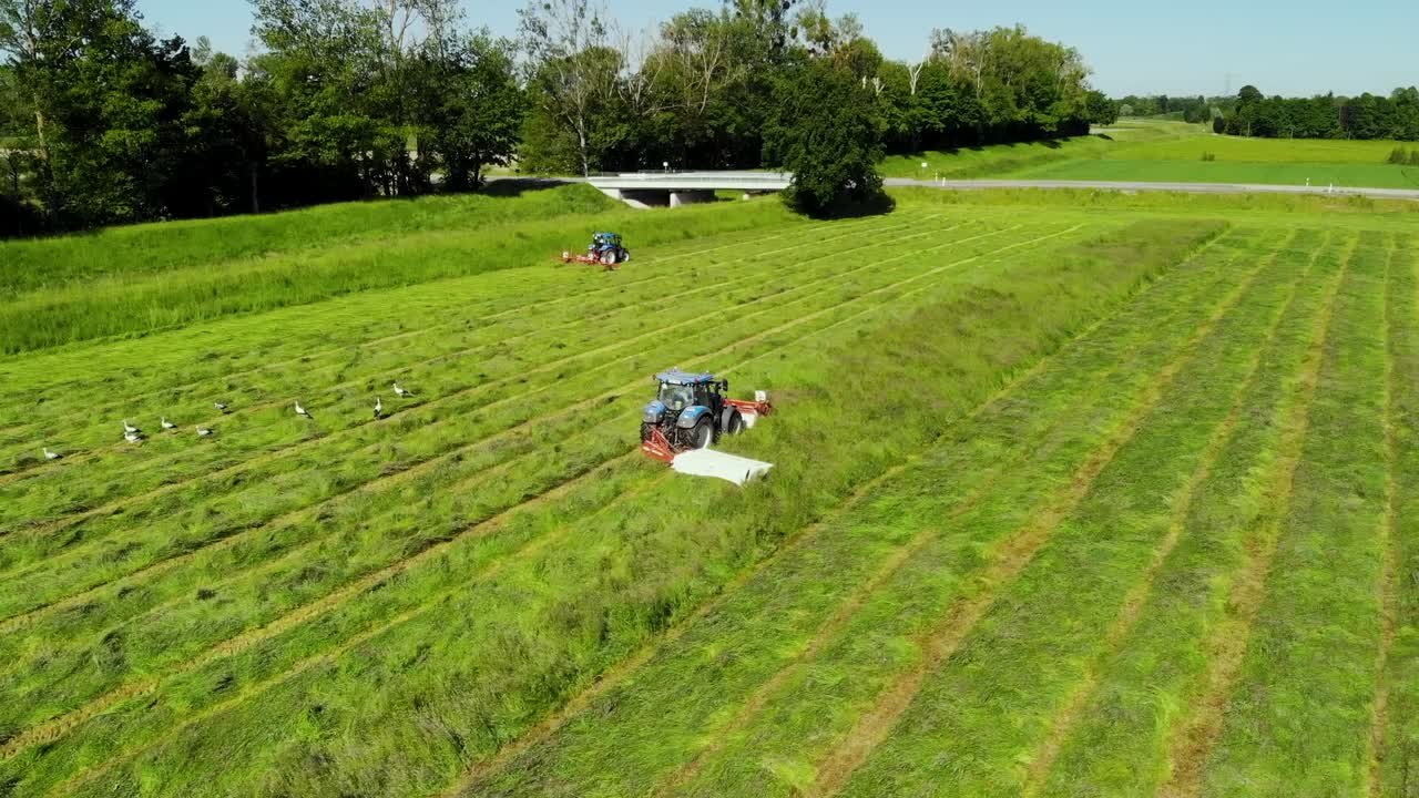 Hay tedder and mower in action filmed from above during hay harvest