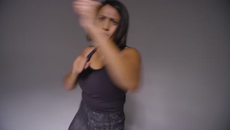 studio portrait of mature woman wearing gym fitness clothing exercising sparring at camera 2