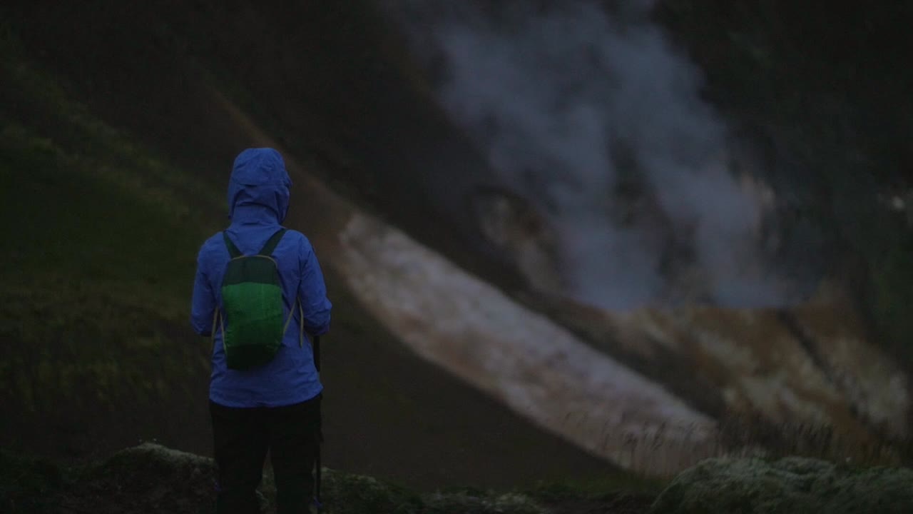 아이슬란드 풍경, 지열 온천 증기 연기, 연기가 피어오르는 것을 보는 한 사람, 카메라 기울기, 어둡고 변덕스러운 저녁 분위기