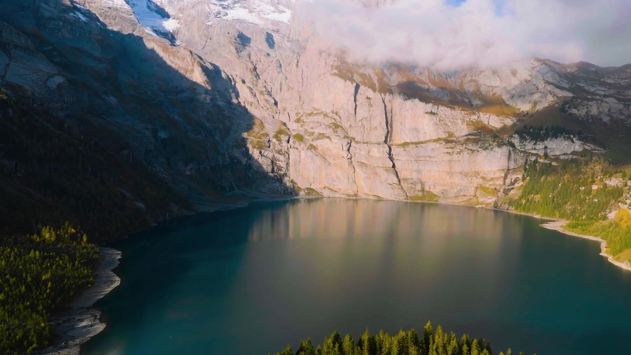 L'acqua scura di montagna riflette imponenti pareti rocciose circondate da fitte foreste di conifere