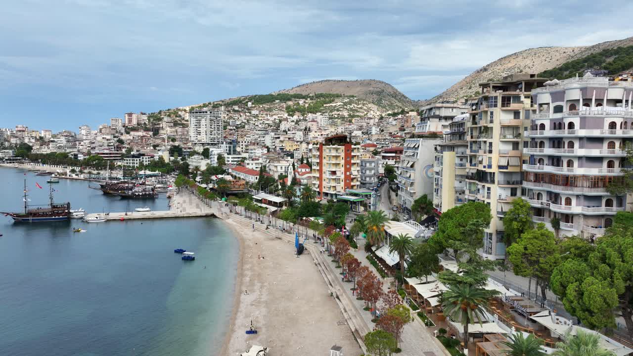 Sandy shoreline and beachfront buildings in Saranda, Albania under overcast sky