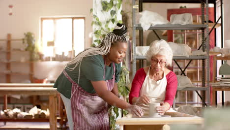 Focused-diverse-female-potters-using-potter's-wheel-in-pottery-studio,-slow-motion