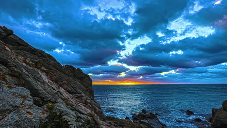 Zeitraffer-Des-Goldenen-Sonnenuntergangshimmels-Mit-Sich-Bewegenden-Wolken-über-Meer-Und-Meeresfelsen