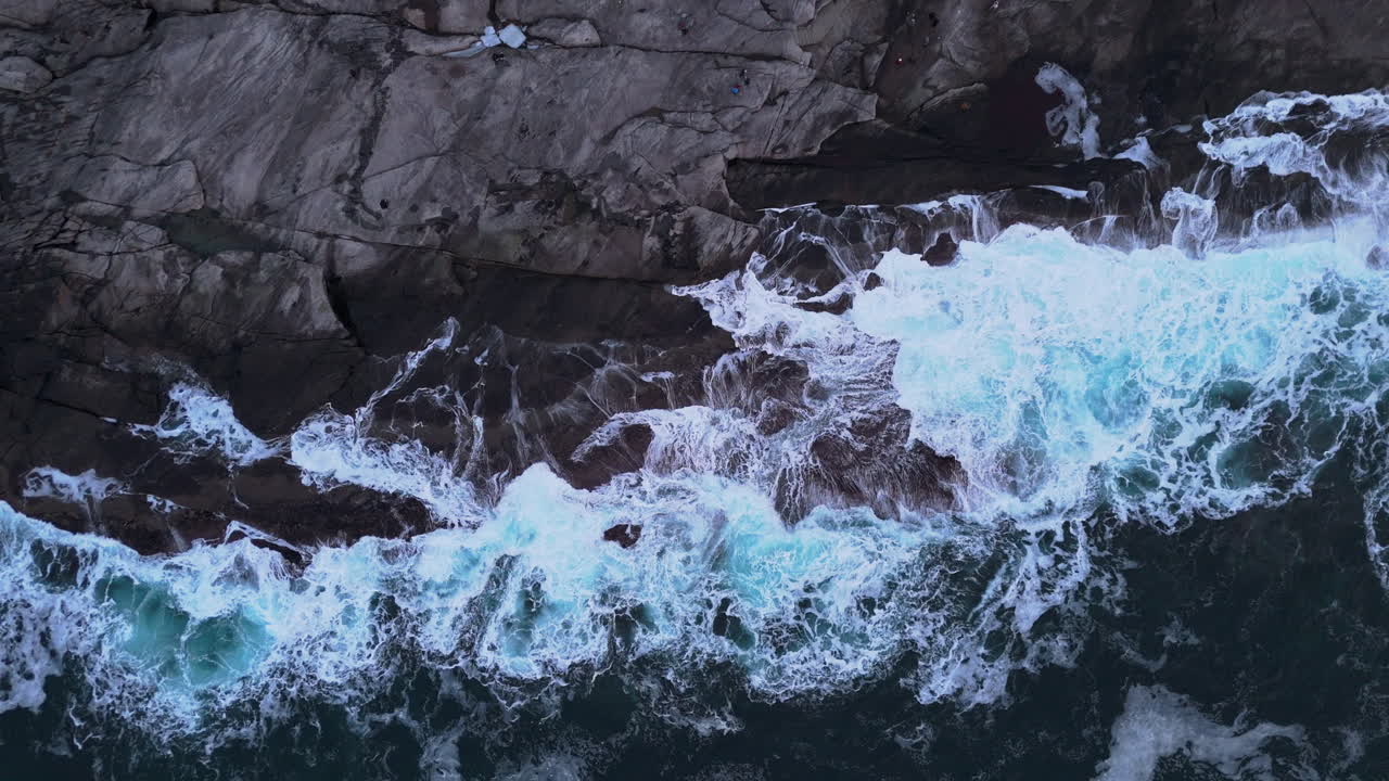 Onde potenti si infrangono contro le rocce frastagliate della spiaggia di Tungeneset, Senja, Norvegia.