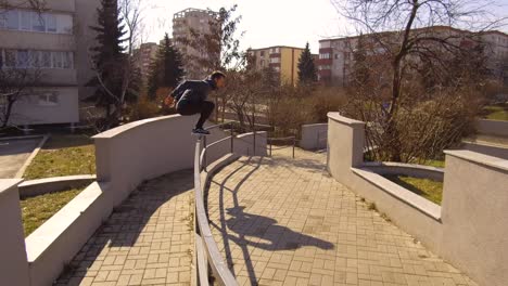 a young man leaps and jumps across walls and railing is a single fluid motion as he runs through the urban landscape