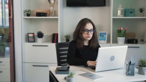 La-Estudiante-Está-Trabajando-En-Una-Computadora-Portátil-En-Una-Habitación-Luminosa,-Se-Distrae-Con-Las-Llamadas-Telefónicas-Entrantes,-Levanta-El-Auricular-Y-Responde-Agresivamente-Que-No-Puede-Hablar