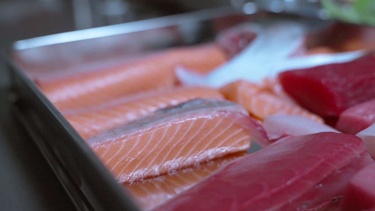 A falling back shot showcasing a variety of raw fish, highlighting their fresh cuts, textures, and vibrant colors, perfect for sushi preparation or other seafood dishes.