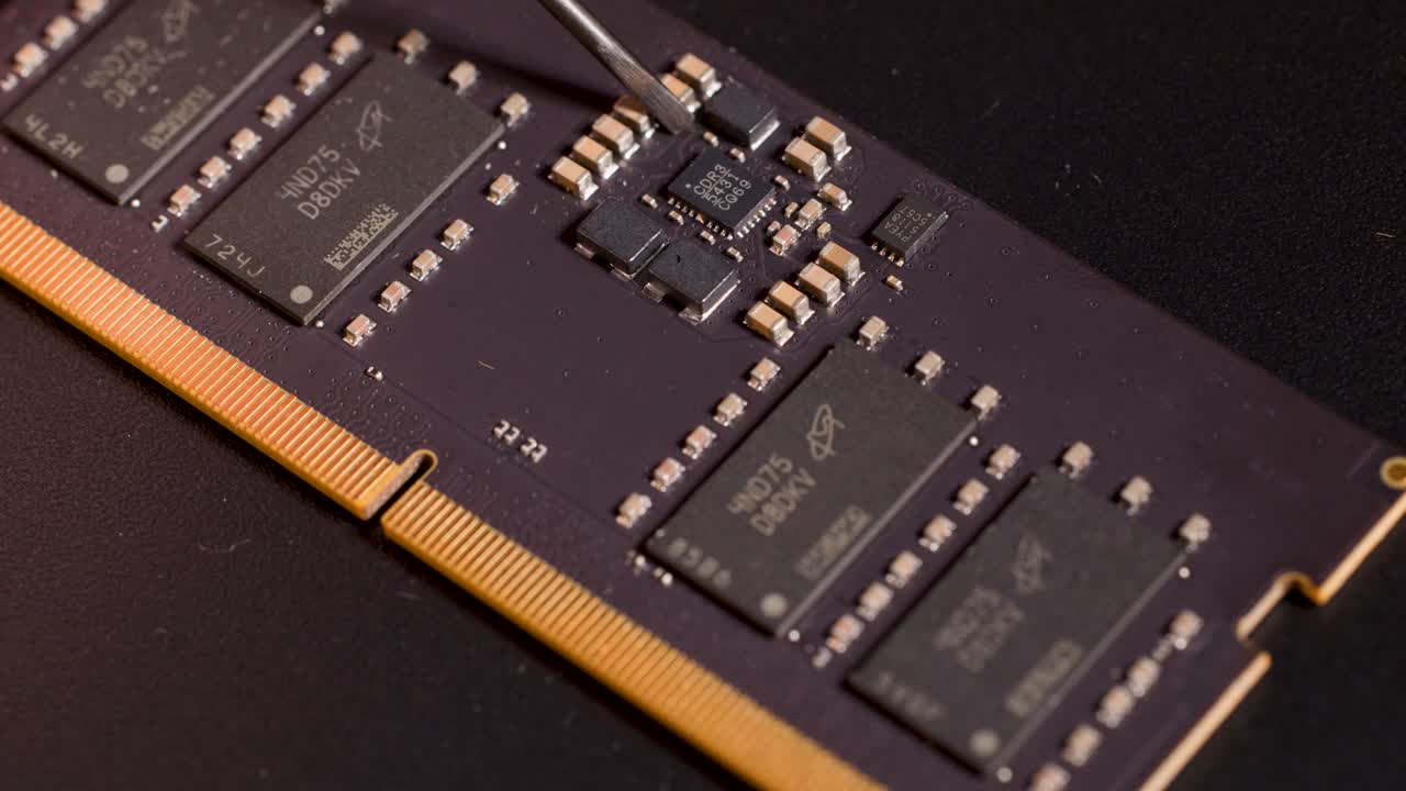 Metal tool precisely points at microchip on memory circuit board under controlled studio lighting