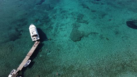 Nautische-Touristen-Entspannen-Und-Schwimmen-In-Der-Blauen-Lagune-Der-Insel-Veliki-Budikovac-Mit-Ihren-Booten-Und-Yachten,-Die-In-Der-Kristallklaren-Bucht-Vor-Anker-Liegen