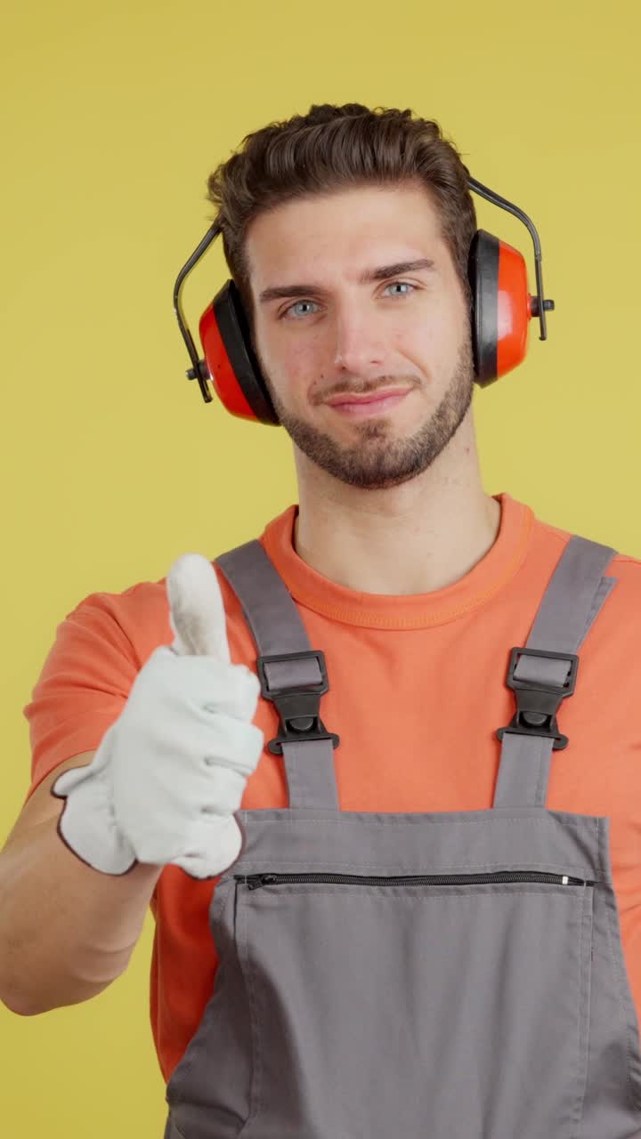 Man in Work Overalls and Ear Protection Giving Thumbs Up